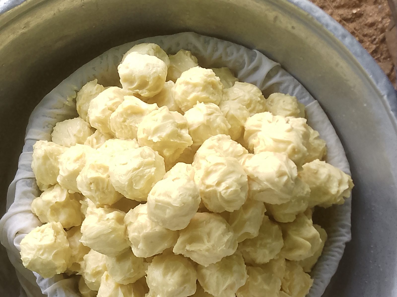 Photograph of hand-formed portions of natural shea butter collected in a metal basin